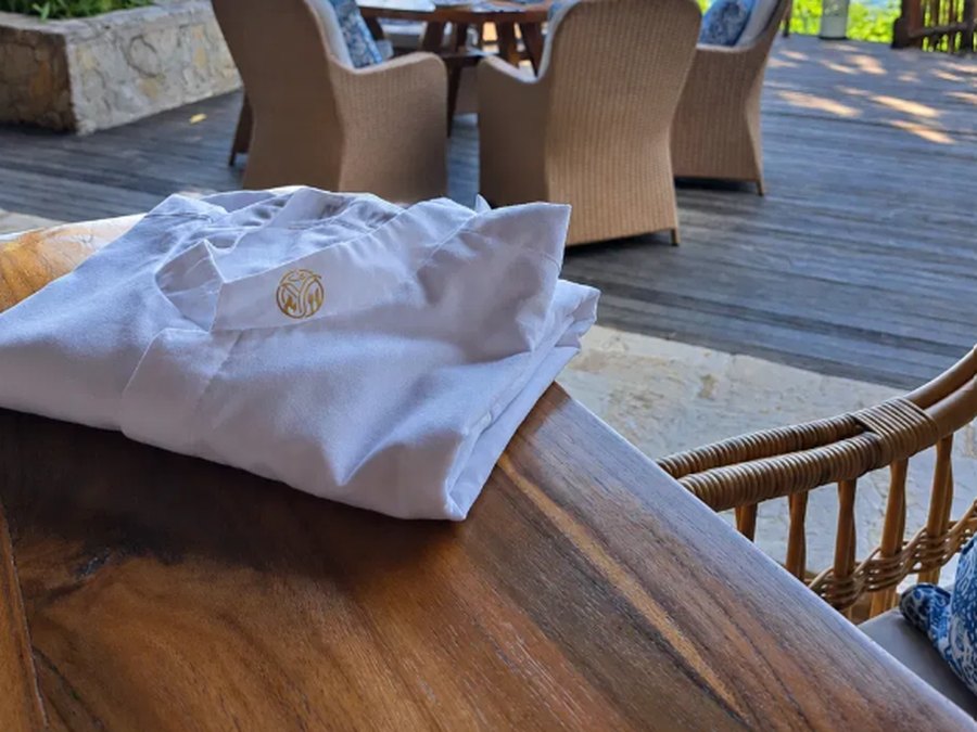 A folded Yunic chef's jacket beside a beachfront dining table